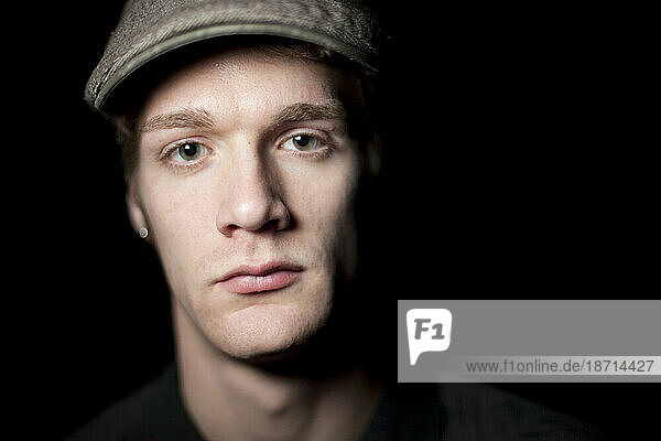 Salmon Arm  BC - A tightly lit close up portrait of a young man wearing sweater and cap.