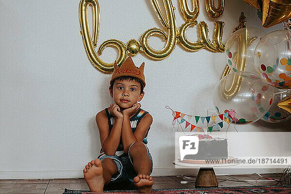 Happy  young multiracial Asian boy sitting with balloons and a c