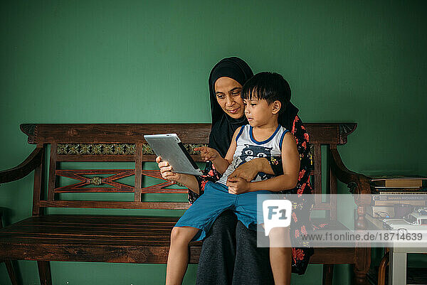 Asian woman with son playing tablet