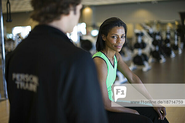 A woman takes a break from working out with a personal trainer.