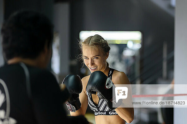 Young female kickboxer in fighting stance in ring with coach  Seminyak  Bali  Indonesia
