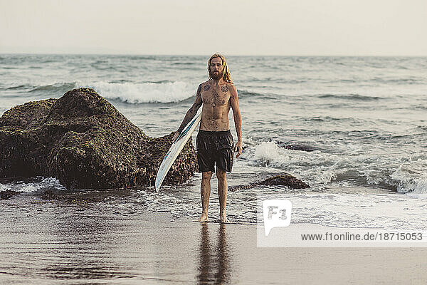 Man with surfboard on beach  Canggu  Bali  Indonesia