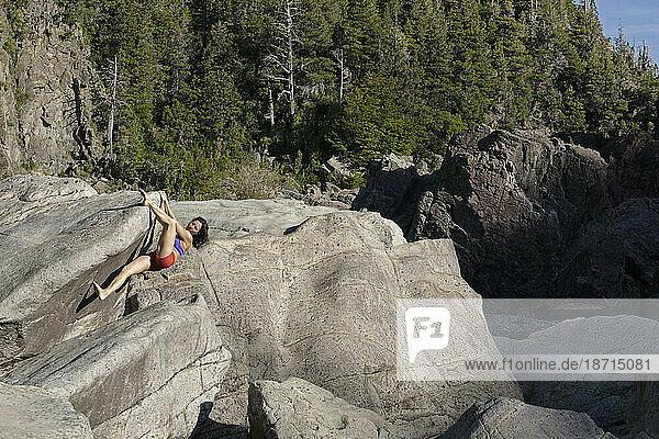 A woman bouldering barefoot at the Los Alerces National Park  Chubut  Argentina.