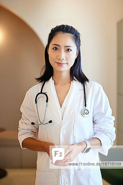 Portrait of female doctor wearing lab coat while standing in clinic