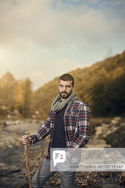 handsome man in nature  holding wooden stick