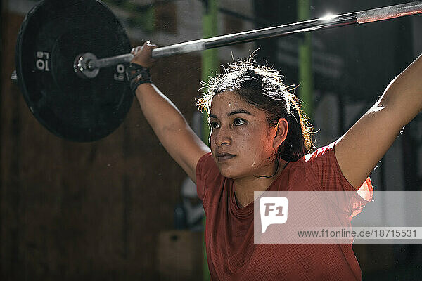Latin woman with dumbbells in the gym doing crossfit. Perú.