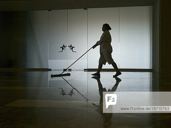 Worker pushes broom as she cleans polished floor in a resort hotel in Cancun  Quintana Roo  Mexico