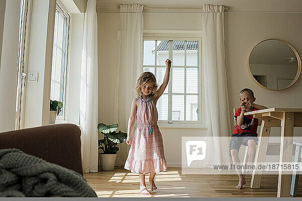 young girl dancing and playing at home with her brother