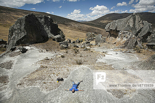 A man lying down between some rocks in Hatun Machay  Peru.