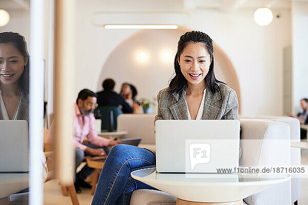 Smiling female entrepreneur working on laptop in office
