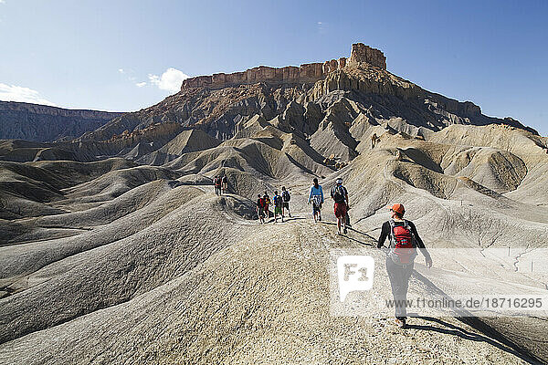 A large group hikes into the mancos shale badlands on BLM land near Factory Butte  Utah.