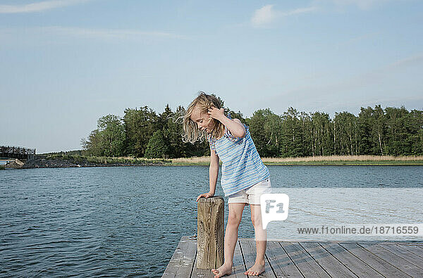 young girl stood on a jetty looking at the water at the beach