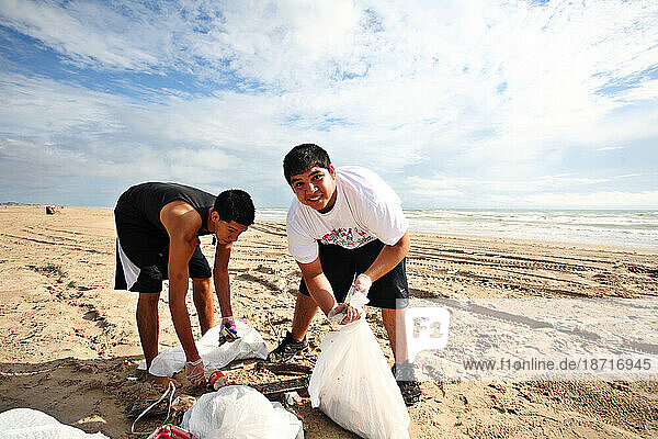 Two friends pick up trash on the beach on S.Padre Island.
