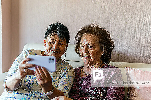 two elderly women with the smartphone taking a photo of themselves