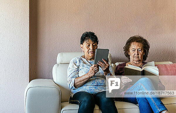 two senior women shopping reading electronic book and paper book