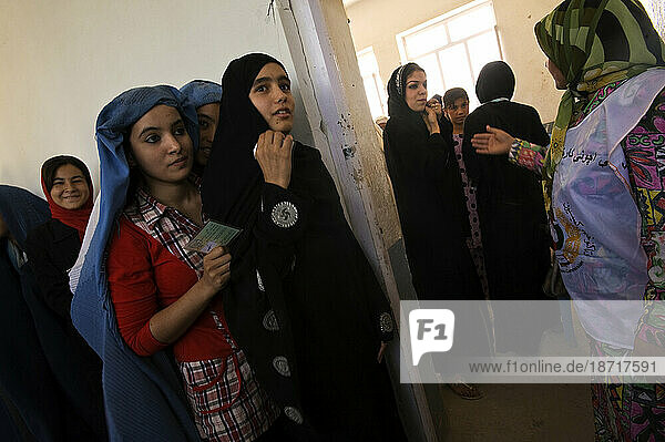 Women hold their registration cards as they wait in line to vote in the Sultan Razia Girls High School on the day of presidential and provincial elections in Mazar-i Sharif  Afghan