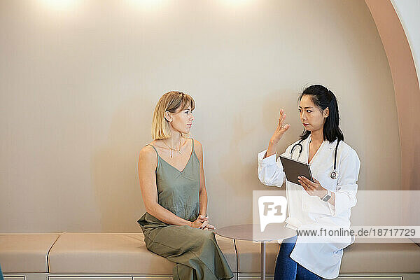 Female doctor with tablet PC explaining to patient in clinic