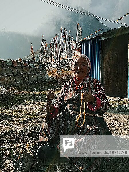 Elderly Woman in cloudy mountains with prayer beads
