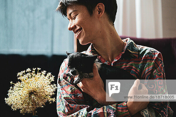 Happy portrait of mixed-race person holding tiny cute puppy dog