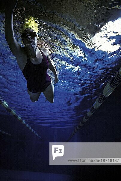 A young woman swims a lap in an Olympic size pool.