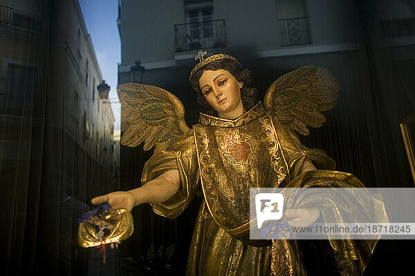 A statue of Saint Raphael Arcangel sits behind a window as the city of Cadiz is reflected in Andalusia  Spain.