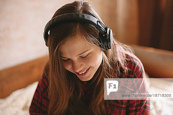 Happy teenage girl listening music on wireless headphones