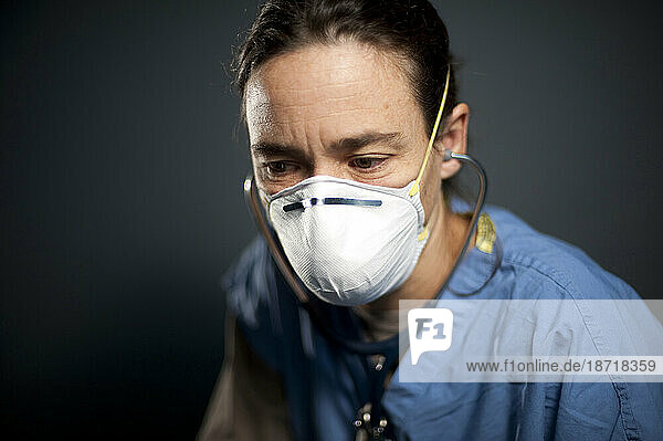 Studio portrait of 42 year old caucasian female registered nurse wearing a N95 mask.
