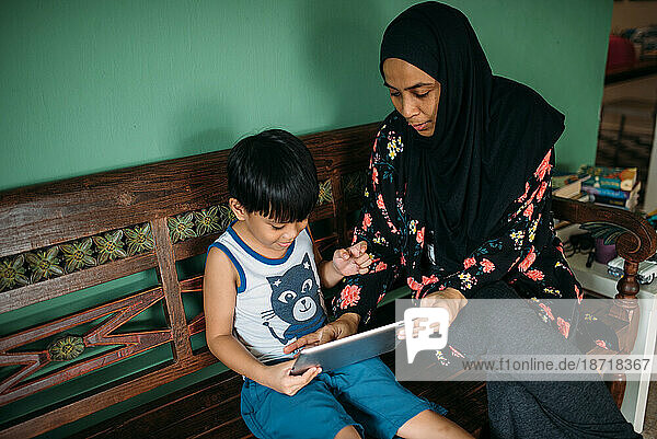 Asian mother and son playing games on smart tablet