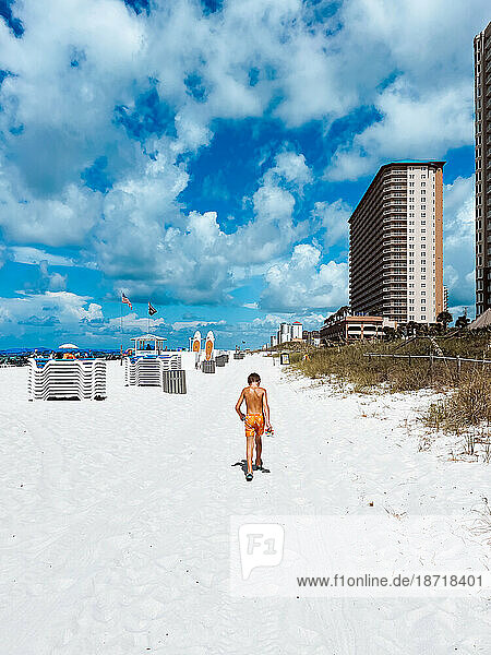 Child walking down white sand beach on summer day