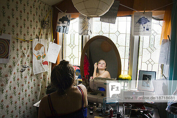 A young woman puts on makeup in her room at home in Seattle  Washington.