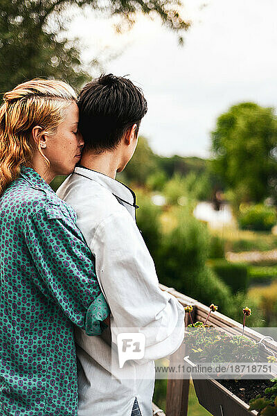 couple hug at home on balcony with view of green trees and lake