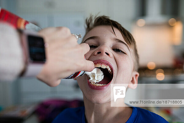 Whipped cream being sprayed into boy's mouth