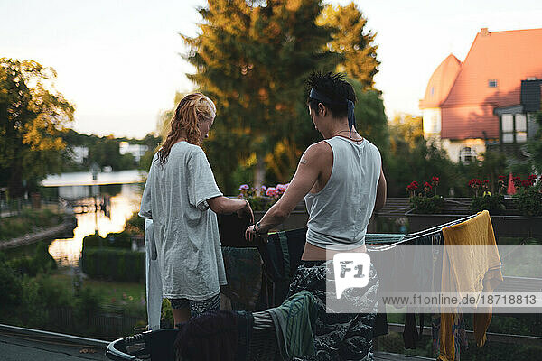 queer couple hang clothes washing together on balcony by lake