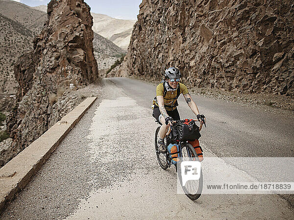 A female bike packer rides along a mountain road in the Atlas Mountain