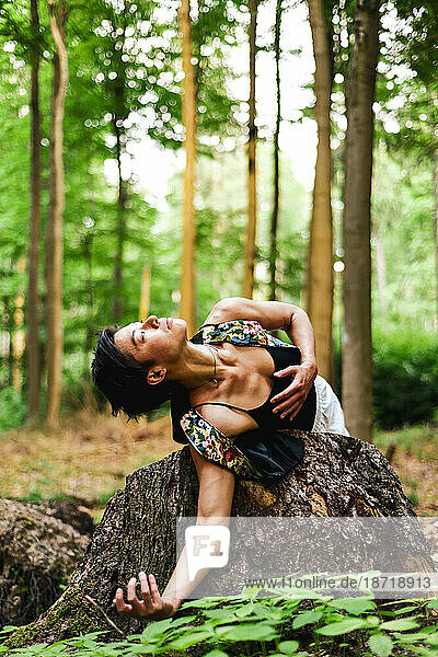 dancer holds heart and leans to earth in green forrest in Europe