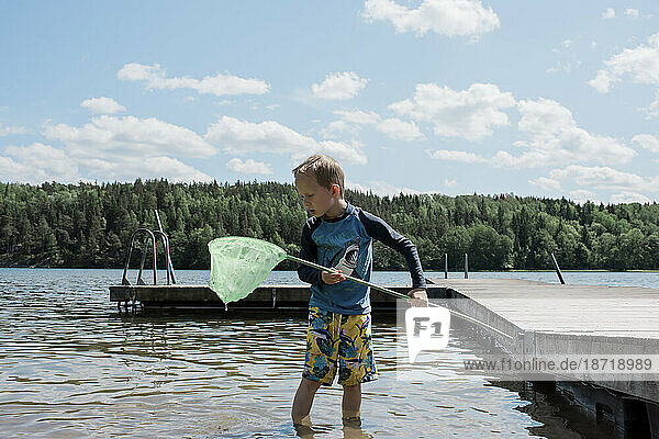 young boy fishing at the beach with a net