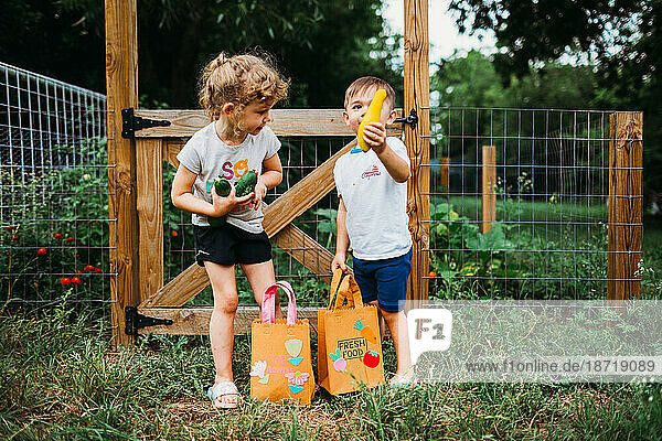 Young boy and girl holding fresh veggies from back yard garden