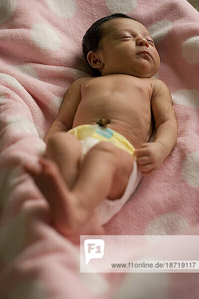A newborn sleeping on a pink blanket