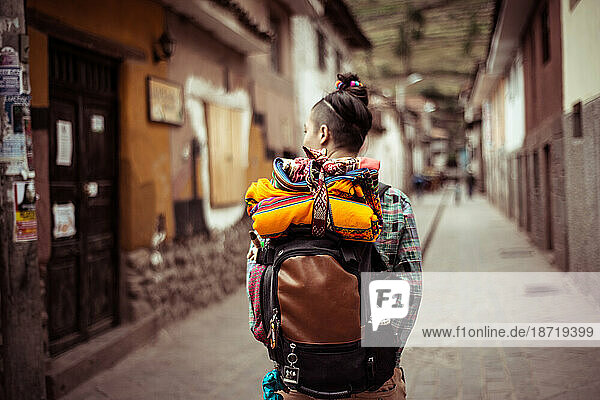 Portrait of funky female traveler with back pack and colourful fabric