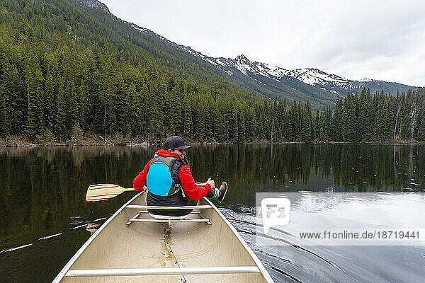 A woman canoeing smiles and dips her foot in the water on Kingdom Lake