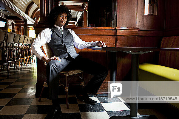 Portrait of a man sitting at a table of a pub in a tie and vest from lifestyle shoot at the Ginger Hop in Minneapolis  Minnesota. (wide angle horizontal)