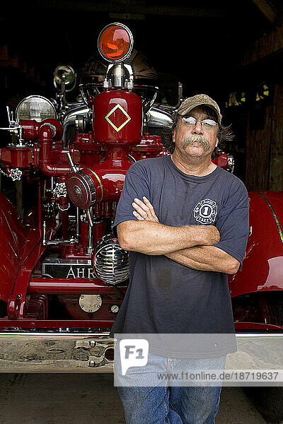 A man who restores fire engines. Here he stands in front of a recently restored 1937 Ahrens-Fox Medole BT.