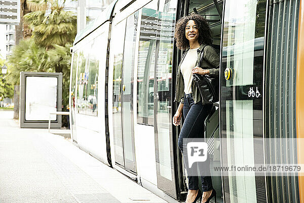 Young confident happy woman getting off a tram.