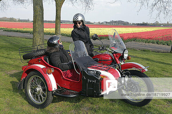 Two young women sharing a moment while sitting in a red motorcycle