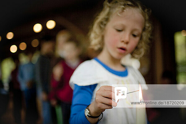 A young girl lights incense at an alter during a Buddhist family retreat on Vashon Island  Washington.