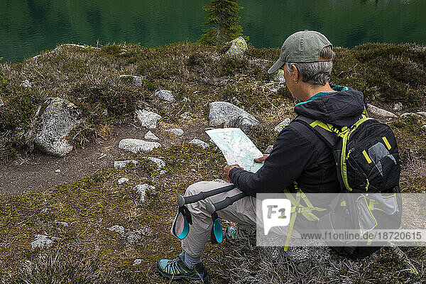 Side view of a women with backpack looking at a map while hiking.
