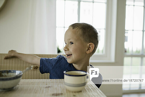 portrait of a young boy playing whilst at the breakfast table