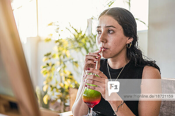 Young woman drinking a three color cocktail