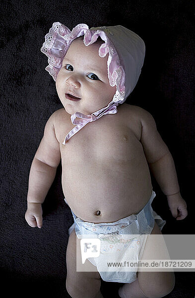 A portrait of a baby girl wearing a pink bonnet.