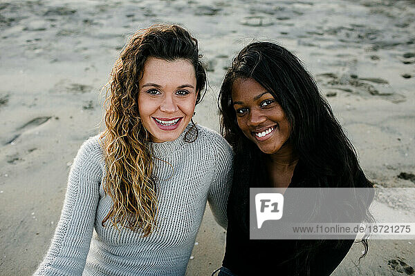 Step mom and step daughter smiling at camera on beach at sunset